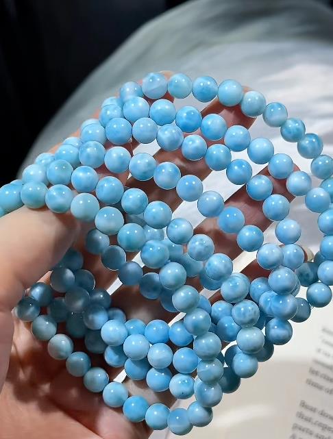 Larimar beads with the blue and white wave pattern, held in hand