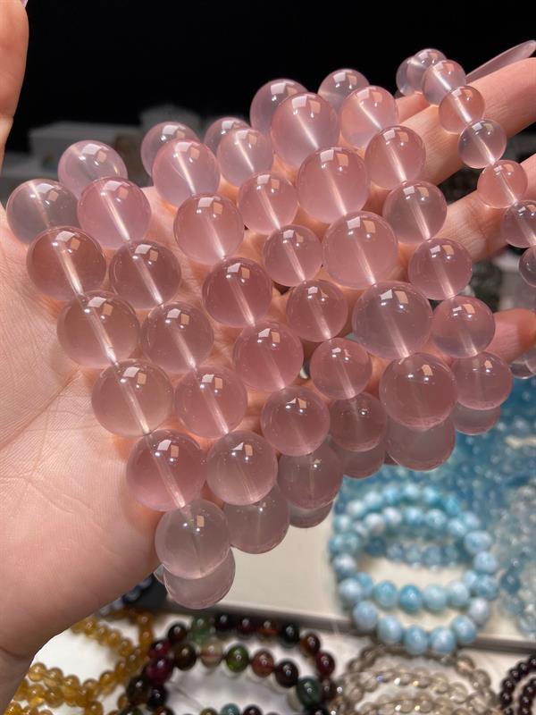 Rose quartz bead strands held in hand at the workshop
