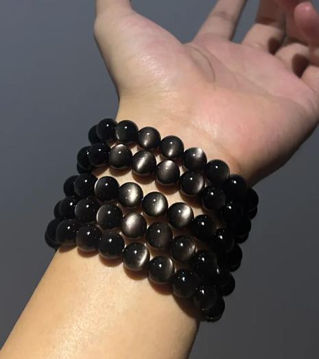 Silver obsidian bracelets stacked on a wrist, showing the silver sheen